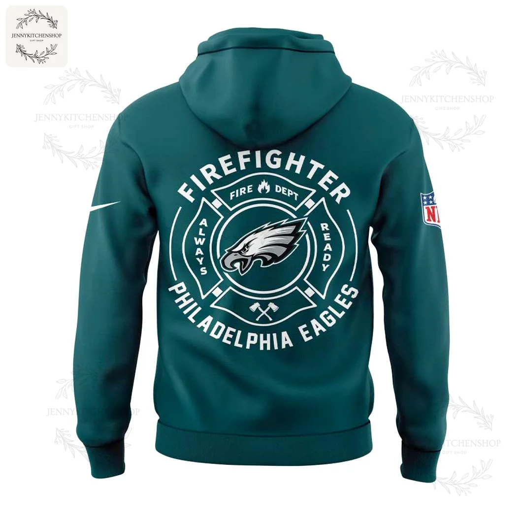 Back view of midnight green hoodie featuring a large white circular firefighter badge with the Eagles logo centered and text reading "FIREFIGHTER" and "PHILADELPHIA EAGLES," plus NFL patch on the sleeve.
