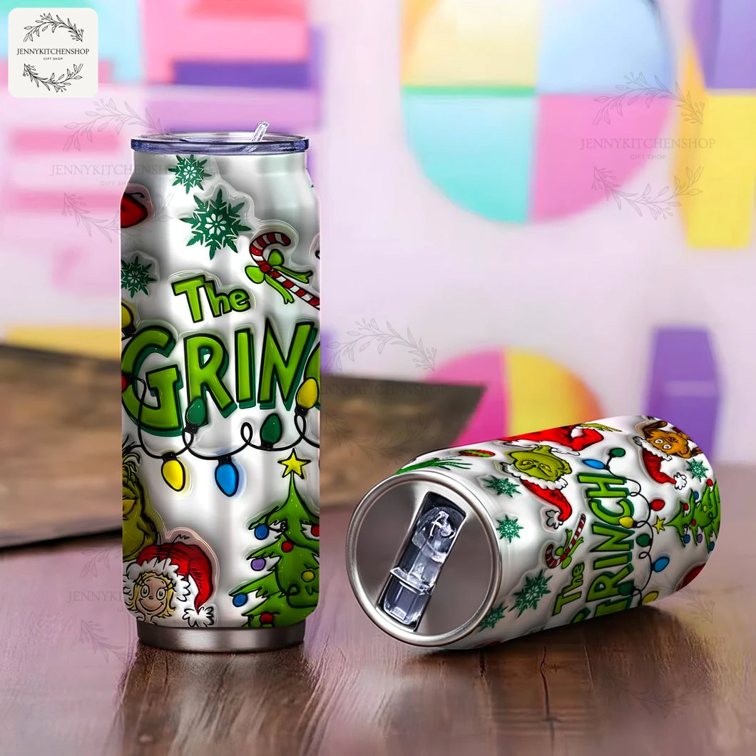 One Grinch can tumbler standing upright and another lying down, displaying the vibrant Christmas design on a wooden table.